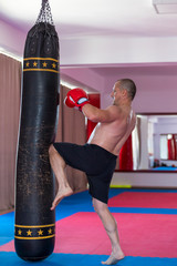 Muay thai fighter hitting the heavy bag in the gym