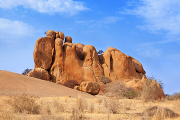 Fototapeta na wymiar Red bald granite peaks on blue sky background, ancient geological formations, orange stones, natural yellow rocks, Erongo mountains, Damaraland, Naukluft national park, Namib Desert, Namibia, Africa