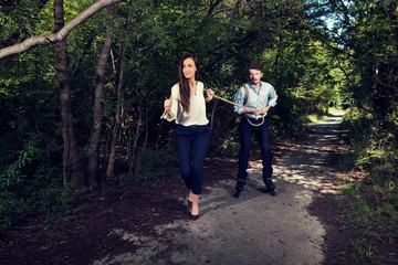 Fototapeta premium Business woman pulling one business man with rope in the city park Selective focus