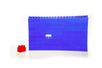 A wall of blue children's colorful plastic building toys bricks, with one missing piece