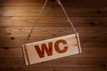 Wooden signboard with the words WC on a rough rope on a beautiful wooden background