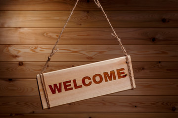 Wooden signboard with the words WELCOME on a rough rope on a beautiful wooden background