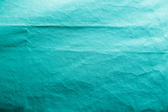 Dirty crumpled turquoise synthetic fabric texture with a well-traced light and shadow pattern