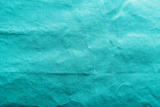 Dirty crumpled turquoise synthetic fabric texture with a well-traced light and shadow pattern
