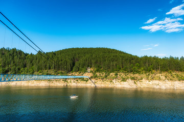 Fisherman boat crossing river under suspension bridge