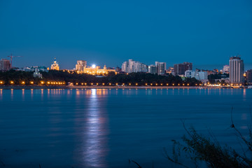 Naklejka premium Night View of the city of Khabarovsk from the Amur river. Blue night sky. The night city is brightly lit with lanterns. The level of the Amur river at around 159 centimeters.