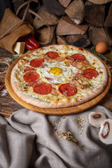 Pizza with egg against the background of firewood and sack
