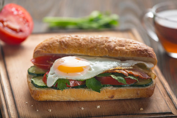 Sandwich with egg, bacon, vegetables and herbs