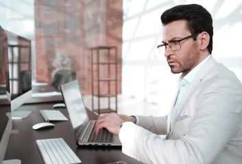 behind the glass.serious businessman typing on a laptop