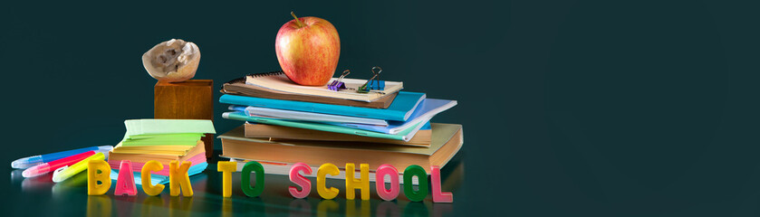 Back to school. Still life with school supplies. Green background. Notebooks, notebooks, felt-tip pens.