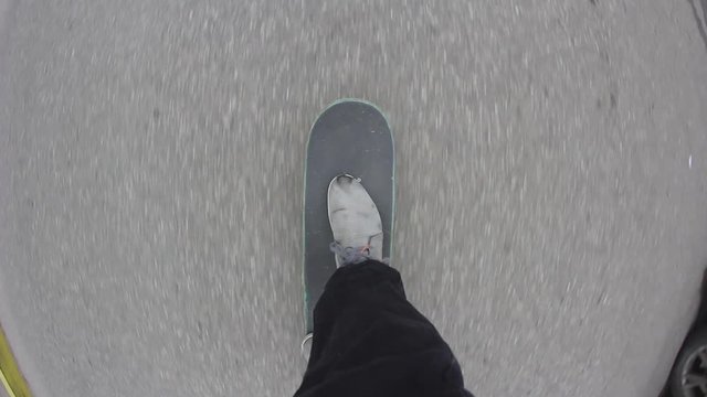 Point of view of skateboarder riding skateboard on the city sidewalk. Skater rolling freestyle in urban environment. Young man holding balance on board, extreme sport