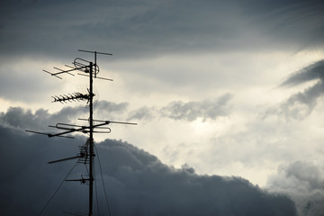 A bunch of antennas against a stormy sky.