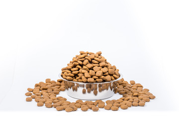 Full Cup with a slide of dry pet food isolated on white background. Metal bowl for cat or dog. The concept of proper nutrition, abundance of food, the harm of overeating, health hazards. Copy space