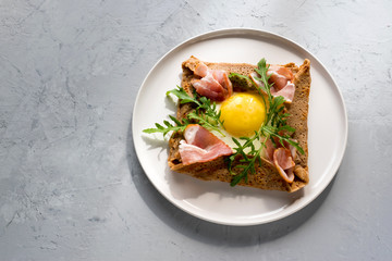 Galette bretonne  with fried eggs, arugula and bacon.
