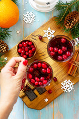 Christmas, Thanksgiving drinks. Hot winter drink with cranberries and cinnamon on wooden table. Top view flat lay with copy space for your text.