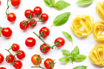 Cherry tomatoes with  basil leaves  and uncooked pasta tagliatelle nest on white background.