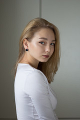 Portrait of the beautiful young woman in white dress looking at camera