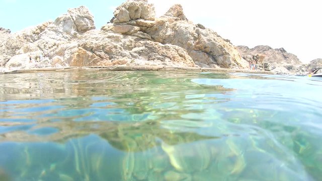 Spain Costa Brava, Cap de Creus, underwater moving camera up to water surface and panning left to see rocky coast in a cove, Cala Culip, Catalonia