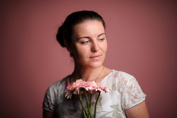 smiling woman with pink flowers. Studio pink background