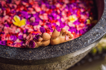 Obraz na płótnie Canvas Attractive Young woman in bath with petals of tropical flowers and aroma oils. Spa treatments for skin rejuvenation. Alluring woman in Spa salon. Girl relaxing in bathtub with flower petals. Luxury