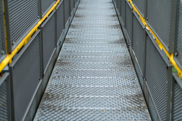 Pedestrian bridge of metal in an industrial facility with yellow railings