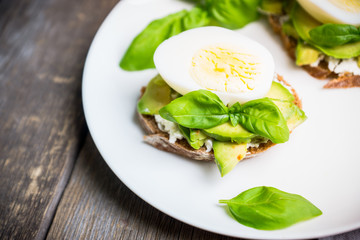 Sandwich with avocado, egg, cheese and basil leaves. Selective focus. Shallow depth of field.