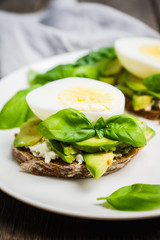 Sandwich with avocado, egg, cheese and basil leaves. Selective focus. Shallow depth of field.