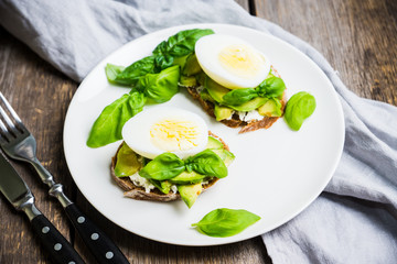 Sandwich with avocado, egg, cheese and basil leaves. Selective focus. Shallow depth of field.