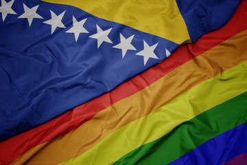 waving colorful gay rainbow flag and national flag of bosnia and herzegovina.