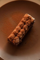 Tiramisu cake on brown background. Minimal modern dessert concept. Top view