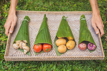 Eco-friendly product packaging concept. Vegetables wrapped in a banana leaf, as an alternative to a plastic bag. Zero waste concept. Alternative packaging
