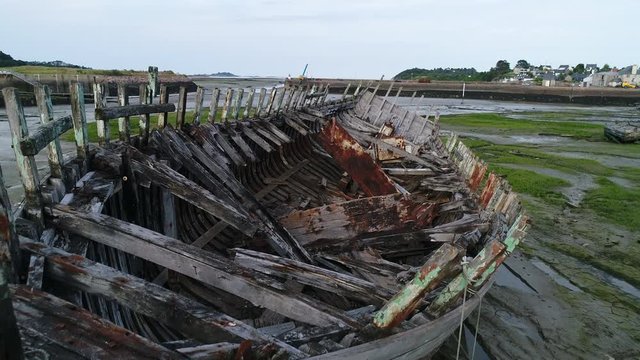 Aerial view. Skeleton of an old abandoned wooden boat. Cemetery of dead ships. The camera moves along the sides of the ship. Closeup dolly shot with drone.