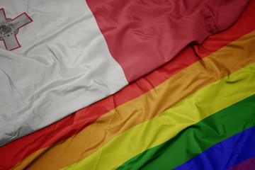waving colorful gay rainbow flag and national flag of malta.