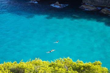 People swimming and diving in turquoise sea of Balearic Islands