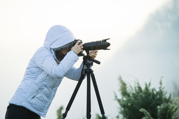 photographer with camera and tripod outdoor taking landscape picture