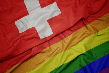 waving colorful gay rainbow flag and national flag of switzerland.