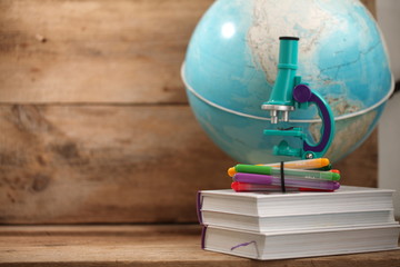 Concert education globe books microscope and pencils on background.