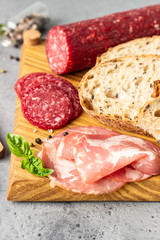 Traditional artisan bread with seeds and pork sausage and salami served on a wooden cutting board. Open sandwich with pork sausage.