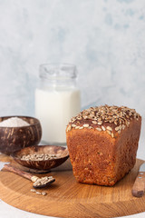 Loaf of wholegrain rye bread with seeds on a wooden cutting board.