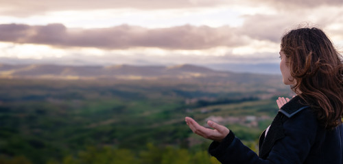 Christian worship and praise. A young woman is praying and worshiping in the evening.