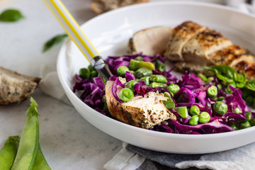 Grilled chicken, red cabbage, green peas and beans on light background. Delicious balanced food concept. Healthy lunch or dinner salad.