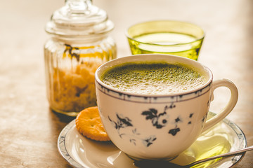 green tea matcha soy latte in a china cup with brown sugar and a glass of water on the side