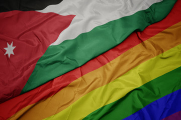 waving colorful gay rainbow flag and national flag of jordan.