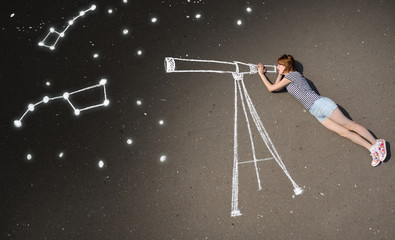Schoolgirl laying on a asphalt, watching stars through a chalk-drawn telescope