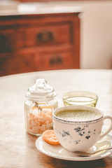 green tea matcha soy latte in a china cup with brown sugar and a glass of water on the side