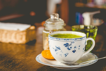 green tea matcha soy latte in a china cup with brown sugar and a glass of water on the side