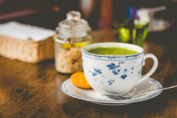 green tea matcha soy latte in a china cup with brown sugar and a glass of water on the side