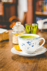 green tea matcha soy latte in a china cup with brown sugar and a glass of water on the side
