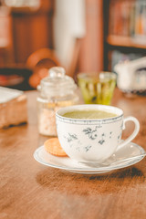 green tea matcha soy latte in a china cup with brown sugar and a glass of water on the side