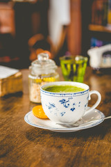 green tea matcha soy latte in a china cup with brown sugar and a glass of water on the side